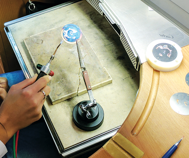 Take a Look inside Cartier’s Maison des Métiers d’Art, here, the white gold dial of an unassembled Ronde Louis Cartier XL Flamed Gold watch being fired with a blowtorch